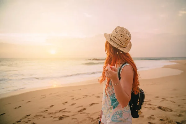 Молода жінка ходить уздовж пляжу на заході сонця, вид ззаду — стокове фото