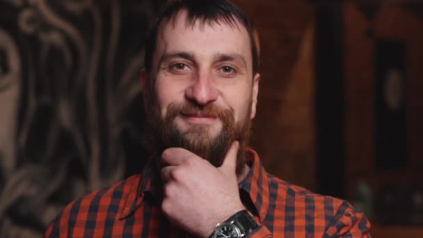 Joven hombre barbudo maduro acariciando su barba y sonriendo — Vídeos de Stock