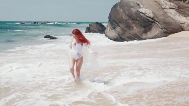 Młoda kobieta biegnie wzdłuż plaży oceanu w słoneczny dzień — Wideo stockowe