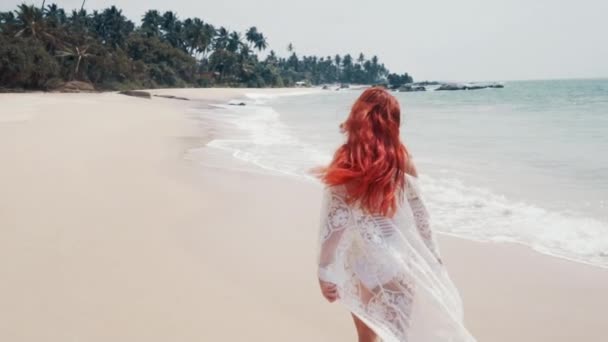 Jonge vrouw loopt langs het strand van de Oceaan op een zonnige dag — Stockvideo