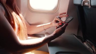 genç kadın bir smartphone bir uçak uçuş sırasında kullanır.