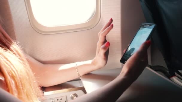Mujer joven utiliza un teléfono inteligente durante un vuelo en avión — Vídeos de Stock