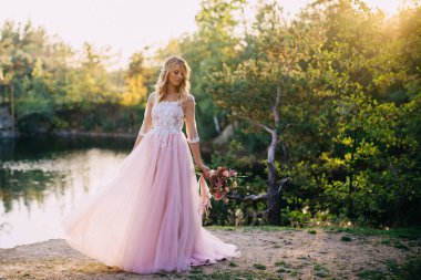 doğa arka plan üzerinde elinde bir buket ile güzel gelin duruyor