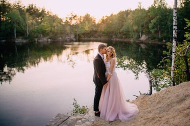 gün batımında göl kıyısında duran yeni evliler