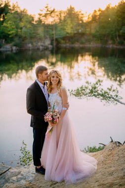 gün batımında göl kıyısında duran yeni evliler