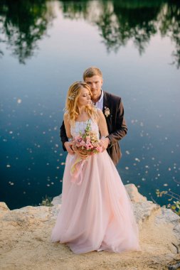 gün batımında göl kıyısında duran yeni evliler