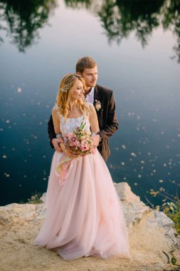 gün batımında göl kıyısında duran yeni evliler