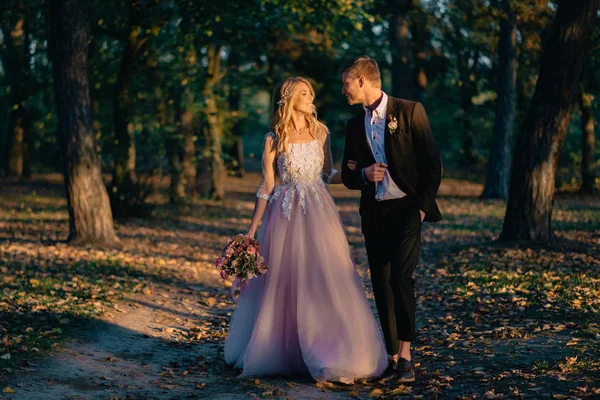 Nygifta promenader i skogen vid solnedgången — Stockfoto