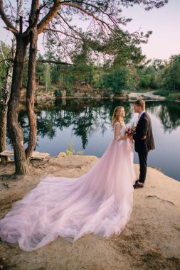 gün batımında göl kıyısında duran yeni evliler