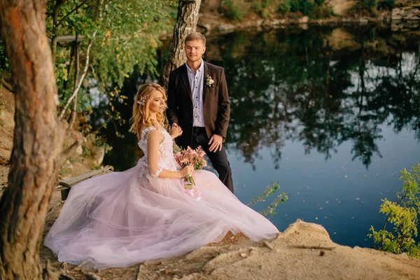 Jeunes mariés sur la rive du lac par une soirée d'été — Photo