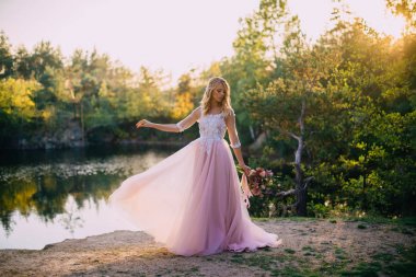 doğa arka plan üzerinde elinde bir buket ile güzel gelin duruyor