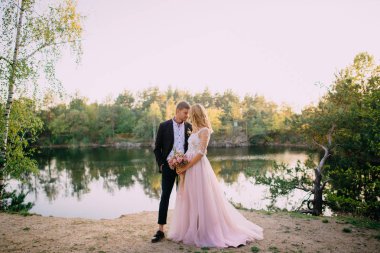 gün batımında göl kıyısında ayakta mutlu yeni evliler