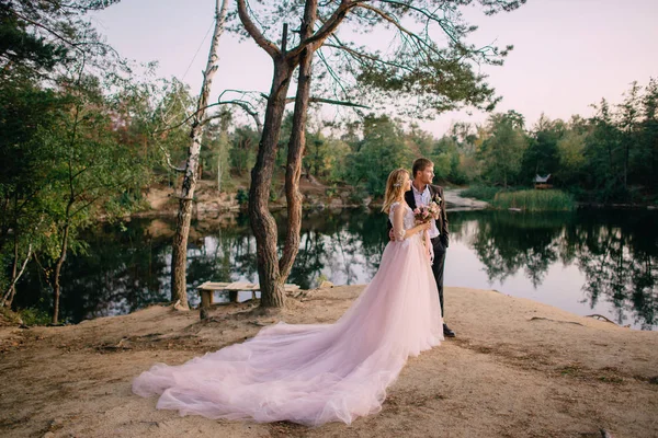 Gün batımında göl kıyısında duran yeni evliler — Stok fotoğraf