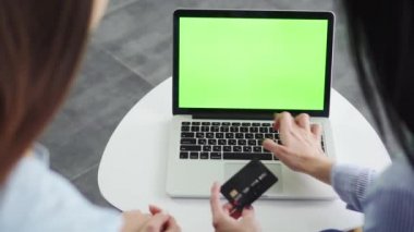 İki kız arkadaşın yakın çekim elleri kredi kartı bilgilerini girerek online alışveriş yapıyorlar, Kara Cuma konsepti.