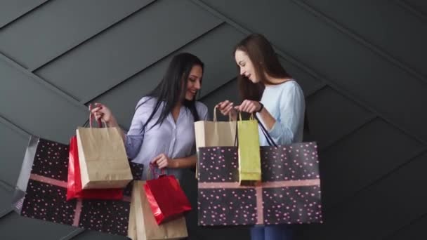 Két vidám barátnő kezében bevásárlószatyrokkal, fekete péntek koncepció — Stock videók