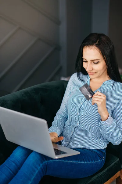 Jovem com laptop detém cartão de crédito em mãos — Fotografia de Stock