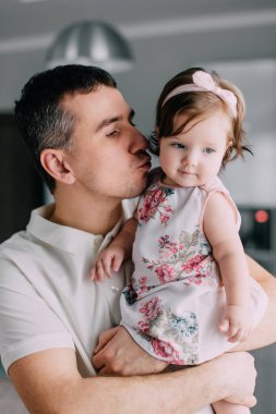 Genç baba ellerini tutuyor. Küçük kız evde, yakın plan.