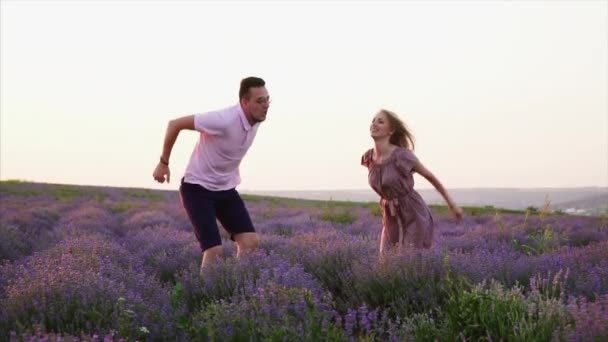 Pareja joven saltando en el campo de la lavanda de floración, cámara lenta — Vídeo de stock