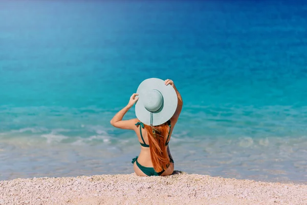 Nuori nainen istuu rannalla selkä kameraan . — kuvapankkivalokuva