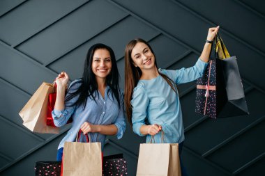 İki neşeli kız arkadaş, siyah arka planda yapılan alımlar için seviniyor.
