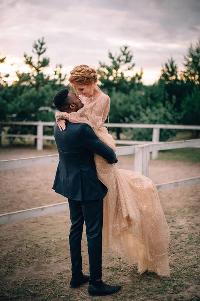 Young bridegroom holds his beautiful bride at the ranch