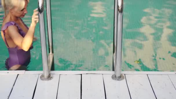 Mujer delgada en traje de baño sale de la piscina — Vídeos de Stock