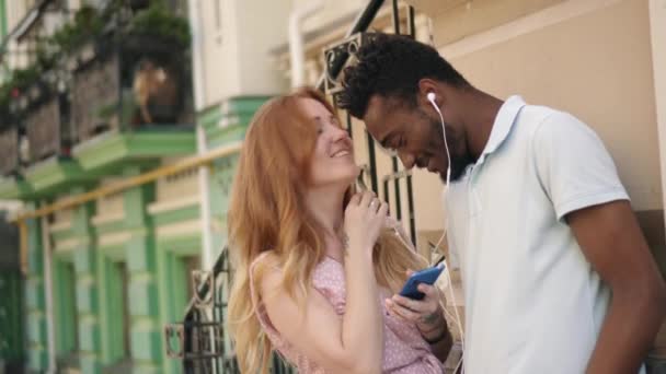 Jeune couple écoutant de la musique sur écouteurs dans la rue — Video