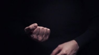 Bir adam siyah arka planda orta parmağını göstererek müstehcen bir hareket yapar.
