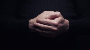 Yakından bakan adam avucunun içine vurur, siyah arka planda kendini izole eder.