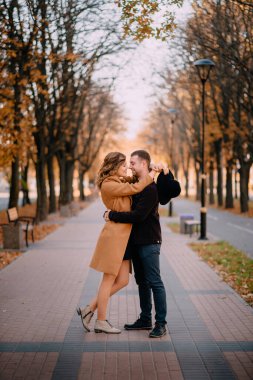 Romantik genç çift bir sonbahar günü parkta sarılıyorlar.