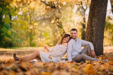 Aşıklar sonbahar parkındaki ağacın yanında oturuyorlar..