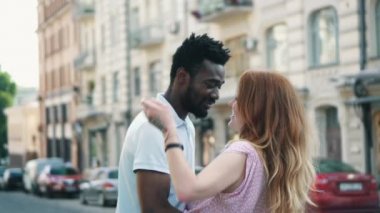 Mutlu genç çift bir yaz günü şehirde sokakta birbirine sarılır.