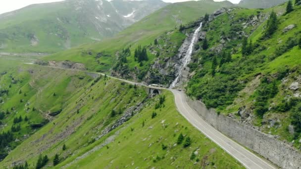 Aerial view of a waterfall over a road in the Carpathian mountains of Romania, drone shot — Stock Video