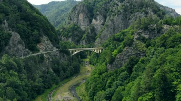 Vista aérea da ponte arqueada que liga uma estrada de montanha nos Cárpatos romenos — Vídeo de Stock