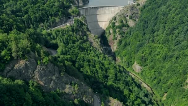 Vista aérea de una presa hidroeléctrica en las montañas cubiertas de bosque — Vídeos de Stock