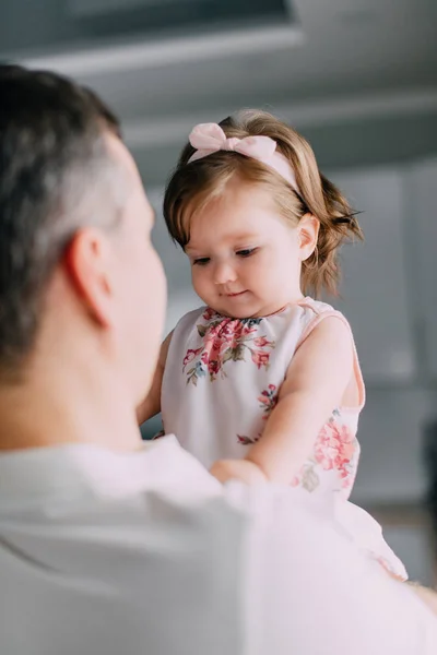 Niña sonriente en brazos de su joven padre en casa —  Fotos de Stock