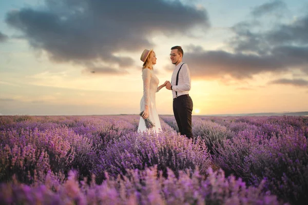 Mutlu yeni evliler günbatımında çiçek açan lavanta tarlasında duruyor. — Stok fotoğraf