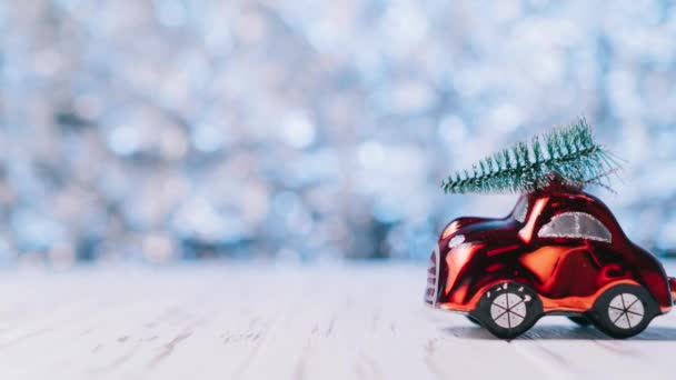 Alto el movimiento, pequeño coche de juguete rojo lleva un árbol de Navidad — Vídeos de Stock