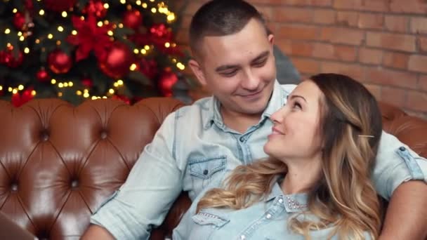 Primer plano hombre besa a su novia sentada en un sofá en casa — Vídeos de Stock