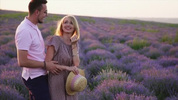 Joven abraza a su novia de pie en un campo de lavanda floreciente — Vídeos de Stock