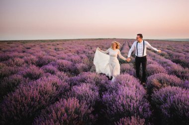 Çiçek açan Lavanta Tarlası boyunca çalışan mutlu yeni evliler