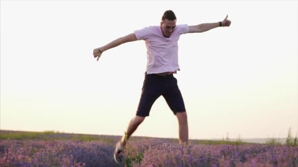 Glad man hoppar upp i blommande lavendelfält, slow motion — Stockvideo