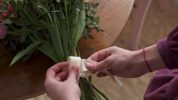 Close-up van vrouwelijke vingers gebonden in Bow lint op boeket — Stockvideo