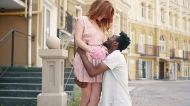 Jonge zwarte man heft zijn vriendin in zijn armen tijdens het lopen op een stad straat — Stockvideo