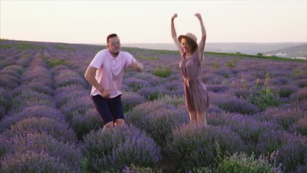 Pareja joven saltando en el campo de la lavanda de floración, cámara lenta — Vídeos de Stock