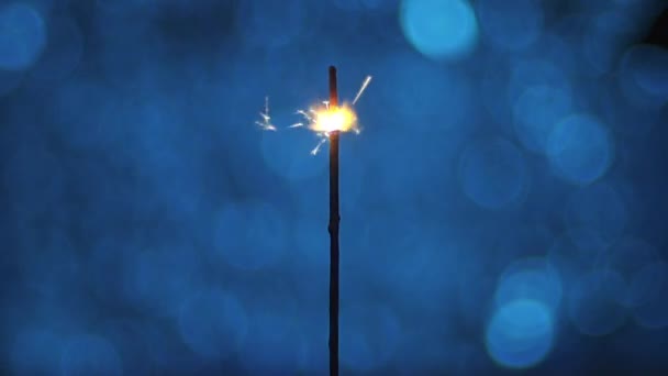 Close-up, faíscas de fogo de Bengala flutuando sobre um fundo azul — Vídeo de Stock