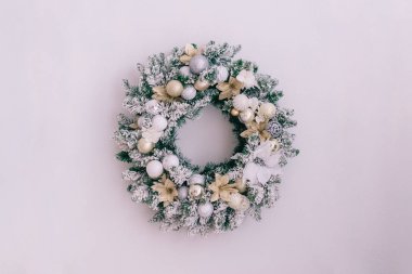 Beyaz bir duvarda karlı bir Noel çelengi. Yazmak için yeri var. Kapat.