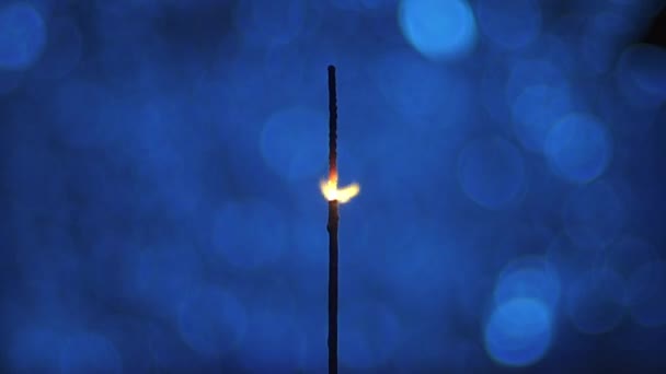 Close-up, faíscas de fogo de Bengala flutuando sobre um fundo azul — Vídeo de Stock