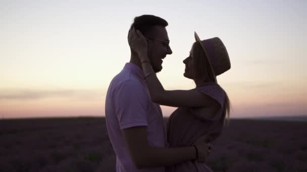 Junges romantisches Paar, das sich in einem blühenden Lavendelfeld umarmt. Silhouette. — Stockvideo
