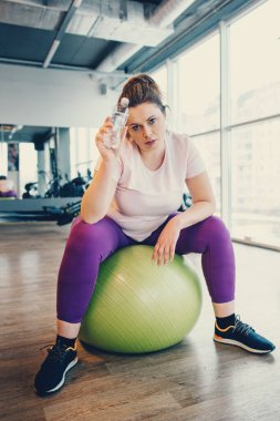 Obez kadın spor salonunda spor salonu topu oturur